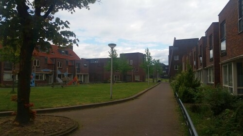 Der 13. Mai 2000 war ein schwarzer Tag in der niederländischen Stadt Enschede. Mitten im Stadtteil Roombeek explodierte die Feuerwerkfabrik S. E. Fireworks. 177 Tonnen Feuerwerkskörper legten das ganze Stadtquartier in Trümmer.

23 Menschen – darunter vier Feuerwehrmänner – starben, 947 Menschen wurden verletzt. 1.500 Wohngebäude wurden durch die Explosion beschädigt oder gerieten durch umherfliegende Feuerwerkskörper in Brand. 200 Wohnhäuser wurden vollständig zerstört und rund 300 als unbewohnbar erklärt. Darüber hinaus wurden über 100 Betriebe beschädigt. In nur einer Stunde verlieren mehr als 1.250 Einwohner ihr Zuhause.

Etwa zwei Drittel des 65 Hektar großen Stadtviertels, welches nördlich an den Hauptbahnhof und die Innenstadt anschließt, waren durch die Explosion betroffen. Mit der Katastrophe waren jedoch auch Chancen und Entwicklungspotenziale verbunden, welche einen Neuanfang für das durch die sterbende Textilindustrie geprägte Quartier bedeuten.

Der für den Wiederaufbau entwickelte Masterplan von Pi de Bruijn (de Architecten Cie. aus Amsterdam - www.cie.nl/projects/53 | Video: https://vimeo.com/51809482) verkörpert eine State of the Art-Stadtplanung. Die 1350 neu errichteten Wohnungen befinden sich in einem durchmischten Gebiet, welches durch kulturelle Angebote, Geschäfte und soziale Einrichtungen ergänzt wird. Freiräume, Wasser und Grün spielen ebenfalls eine große Rolle.

Dabei hat Pi de Bruijn den Einwohnern große Freiheit gelassen, selbst zu bestimmen, wie ihre Nachbarschaft aussehen soll. Üblicherweise macht die niederländische Stadtplanung vergleichsweise viele Vorgaben und lässt wenige Freiheiten. In Roombeek konnten rund 50 Prozent der Einwohner ihre neuen Wohngebäude vollkommen frei entwerfen, nur für die Bereiche an den Hauptverkehrsachsen wurden strengere Vorgaben gemacht. Das Straßennetz wurde exakt in der Form wieder aufgebaut, in der es vor der Explosion existierte. Dies sollte den ehemaligen Bewohnern ein rasches Ankommen und Einleben ermöglichen. Zudem wurde versucht, die vereinzelten noch stehenden Gebäude, soweit es geht, zu sichern und weiterzuentwickeln.