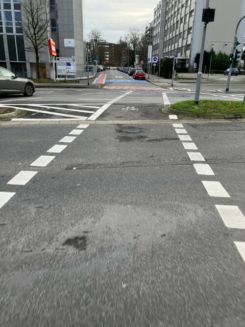 Teilgesicherte Kreuzung am Knotenpunkt Berliner Platz / Fliethstraße in Mönchengladbach. Die Protektion wird bis zum Knotenpunkt vorgezogen, eine geschützte Kreuzung nach niederländischem Vorbild aber nicht umgesetzt. Die Radverkehrsführung mündet in die "Blaue Route", die erste Fahrradstraße in Mönchengladbach, die zudem mit blauen Markierungselementen umgesetzt wurde.